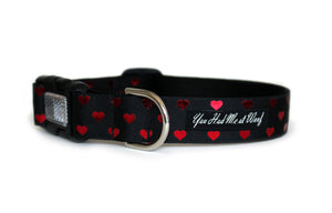 The Secret Valentine Dog Collar in all black with metallic red hearts that repeat across the length of the collar.