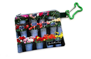 Combination dog bag and dog treat holder with beautiful photographic image of assorted blooming flowers in galvanized buckets outside of a flower shop, featuring zipper closure and a bone-shaped carabiner that attaches to a leash handle.