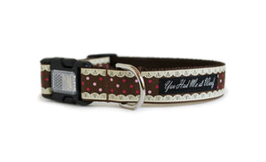 Christmas Dog Collar with brown webbing and white detailing that looks like laced frosting along the edges and red and pink dots in between, featuring an optional reflective buckle for safety.