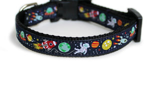 The Outer Space Dog Collar with soft navy blue trim, featuring rocket ships, planets, an alien in a spaceship, and an astronaut, with black webbing underneath.