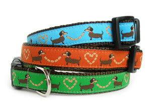 The Sausage Dogs Collar in brown webbing with your choice of blue, orange, green, white or red trim with brown sausage dogs holding sausage links in the shape of hearts.